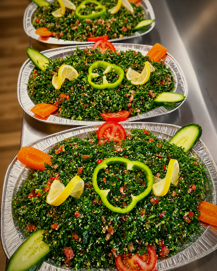 Fresh tabbouleh prepared by ALBAIT ALSHAMI RESTAURANG, garnished with tomato, cucumber and pepper.